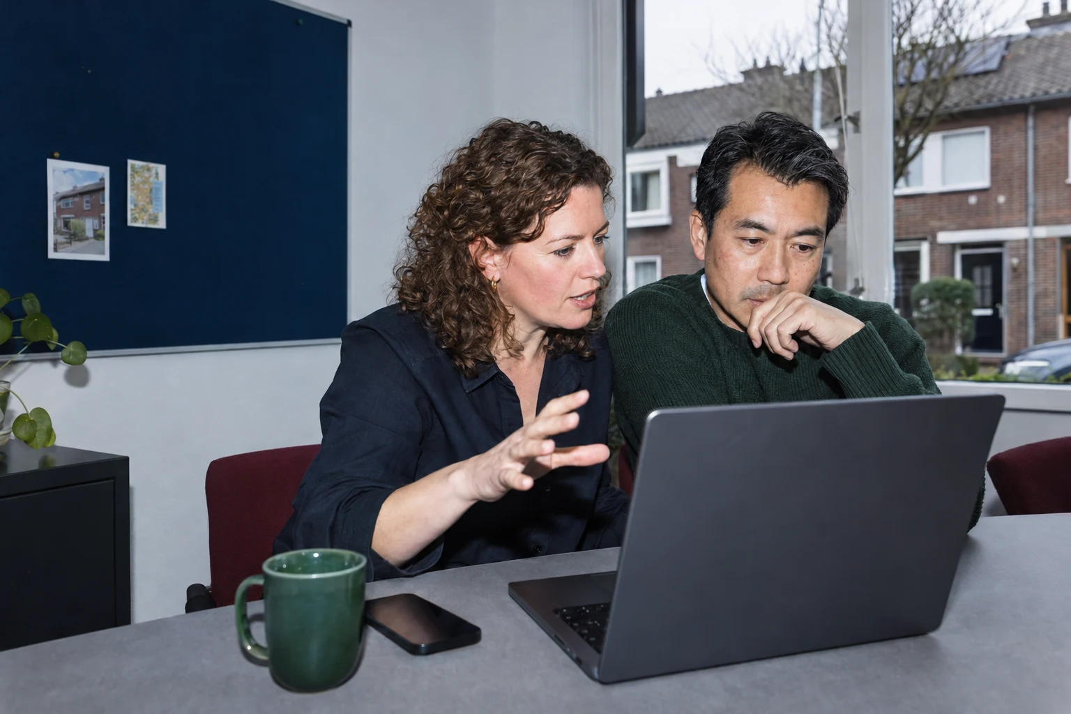 AI-conceptfoto van twee adviseurs die samen een woningdossier bespreken.