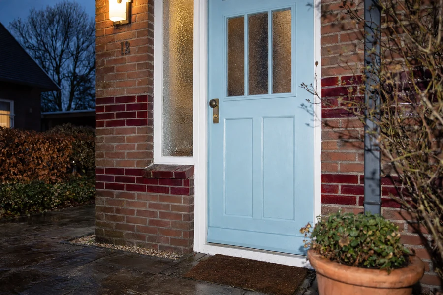 AI concept photo of a pale blue front door and brick facade at dusk.